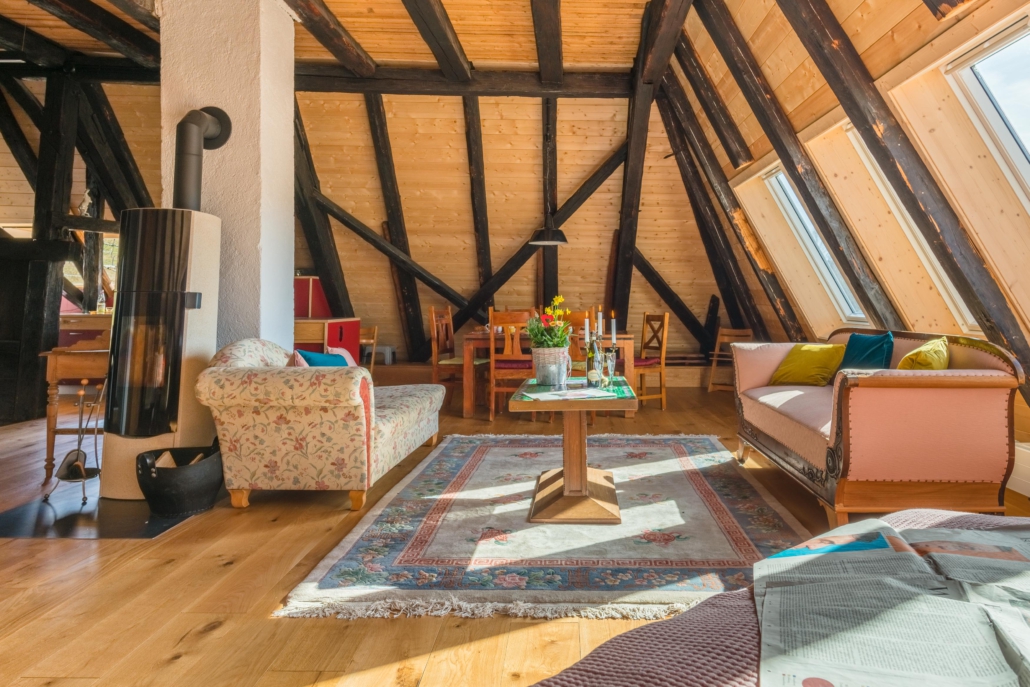 Couchtisch mit 2 Sofas neben dem Kaminofen, dahinter Essbereich