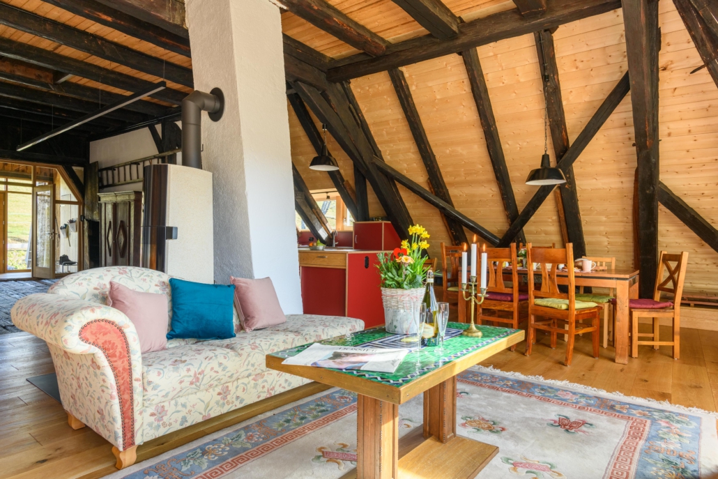 Sofa mit Tisch, im Hintergrund Eingangsbereich, Essplatz und Küchenbereich