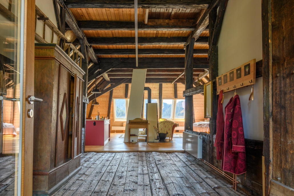 Blick vom Eingang über den 250-Jahre-alten Bohlenboden zum Hauptraum mit Kamin und Panoramadachfenstern