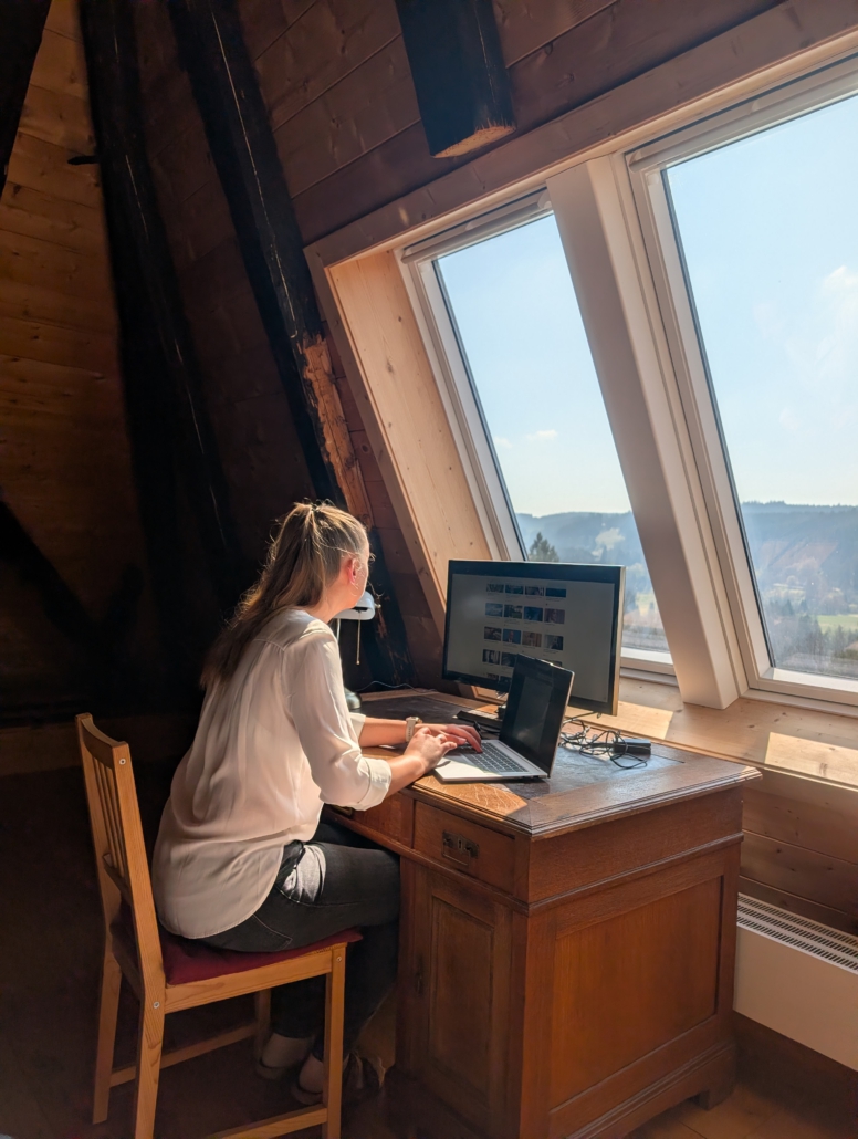 Gast am Schreibtisch mit Laptop und großem Bildschirm