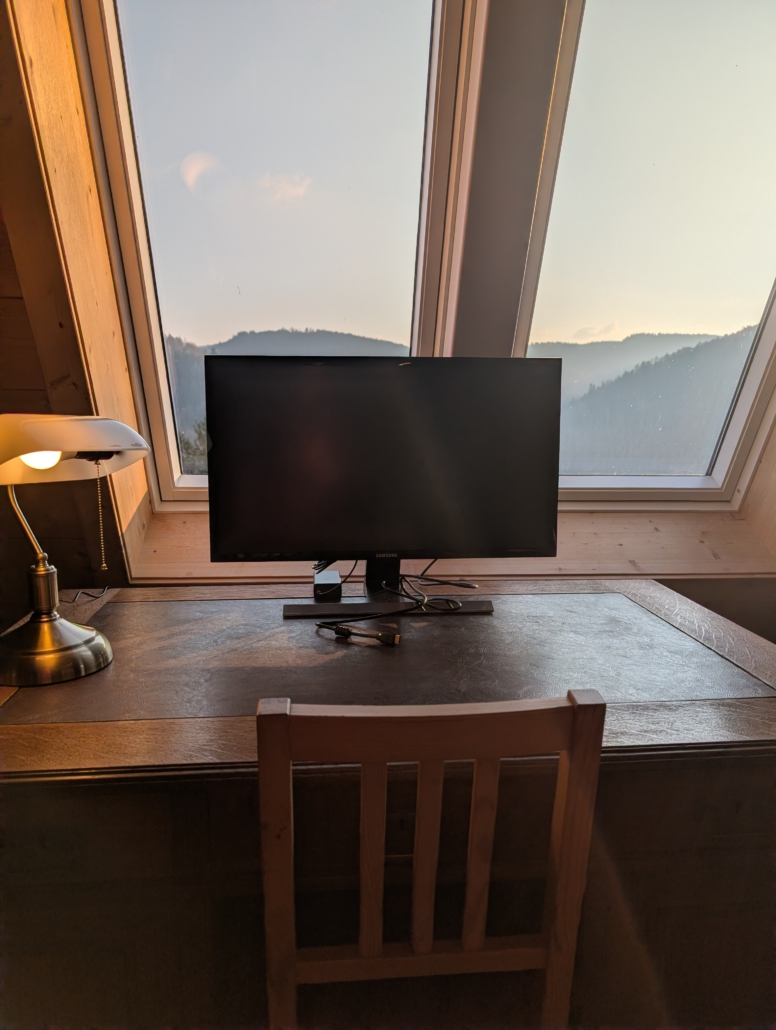 großer Schreibtisch mit Lampe, 27"-Bildschirm, Steckdosenleiste direkt unter dem Fenster