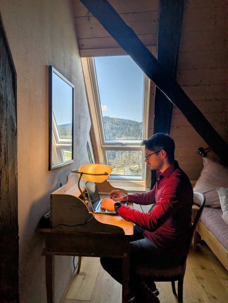 Gast am kleinen Schreibtisch im Schlafzimmer vor dem Fenster