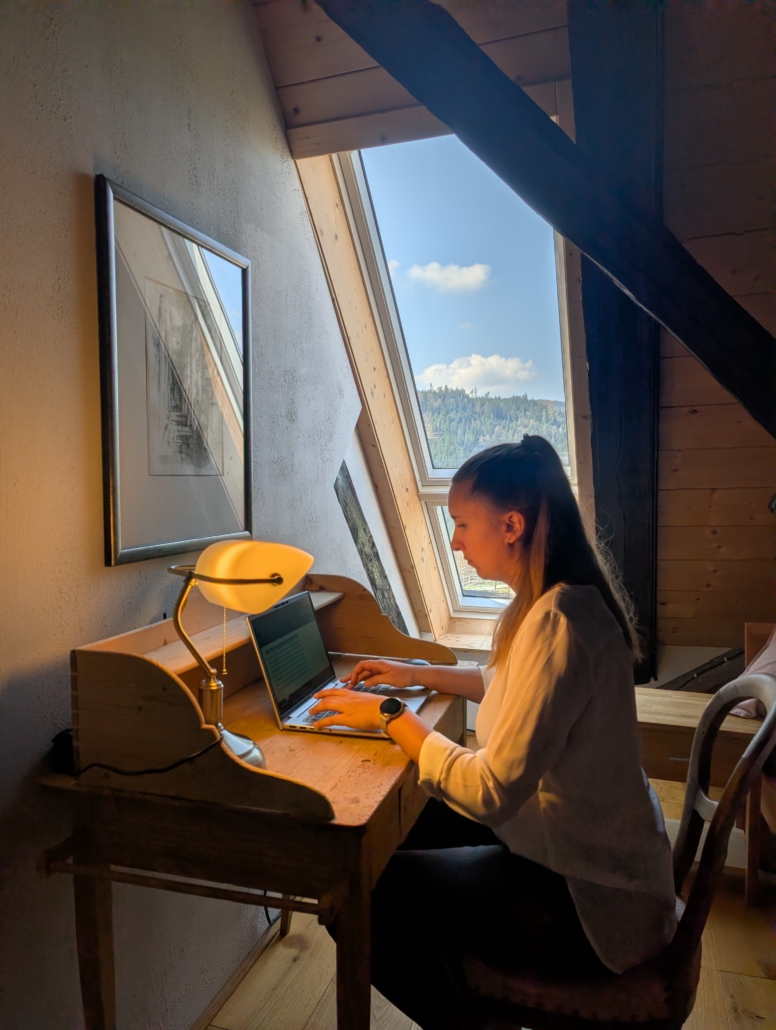 Gast an kleinem Schreibtisch im Schlafzimmer vor dem Fenster