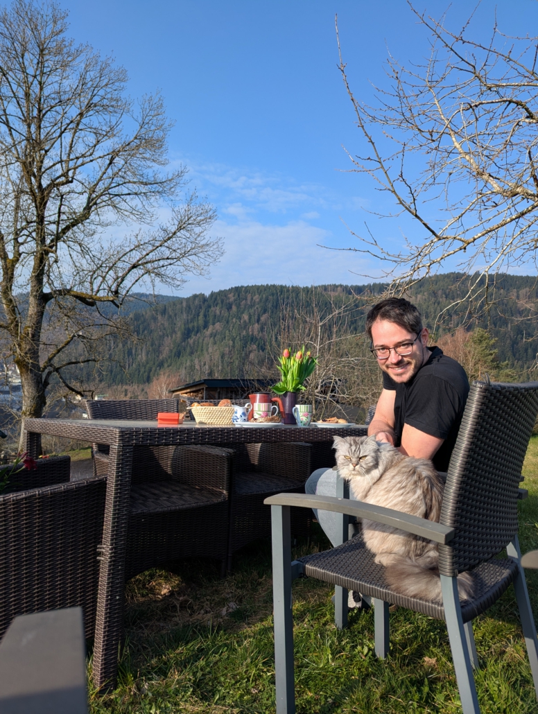 Gast beim Frühstück auf der Terrasse mit Katze