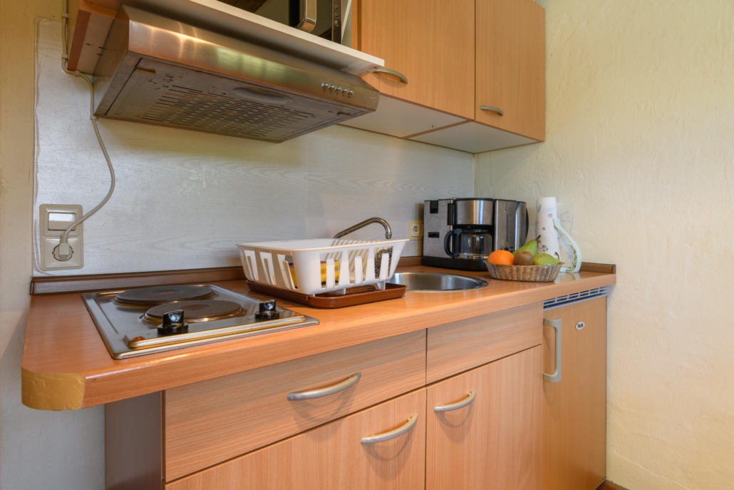 Küchenzeile mit Kochplatten, Spüle, Kaffeemaschine und Wasserkocher